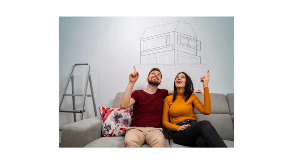 Happy couple planning their new home, pointing at a house sketch on the wall.