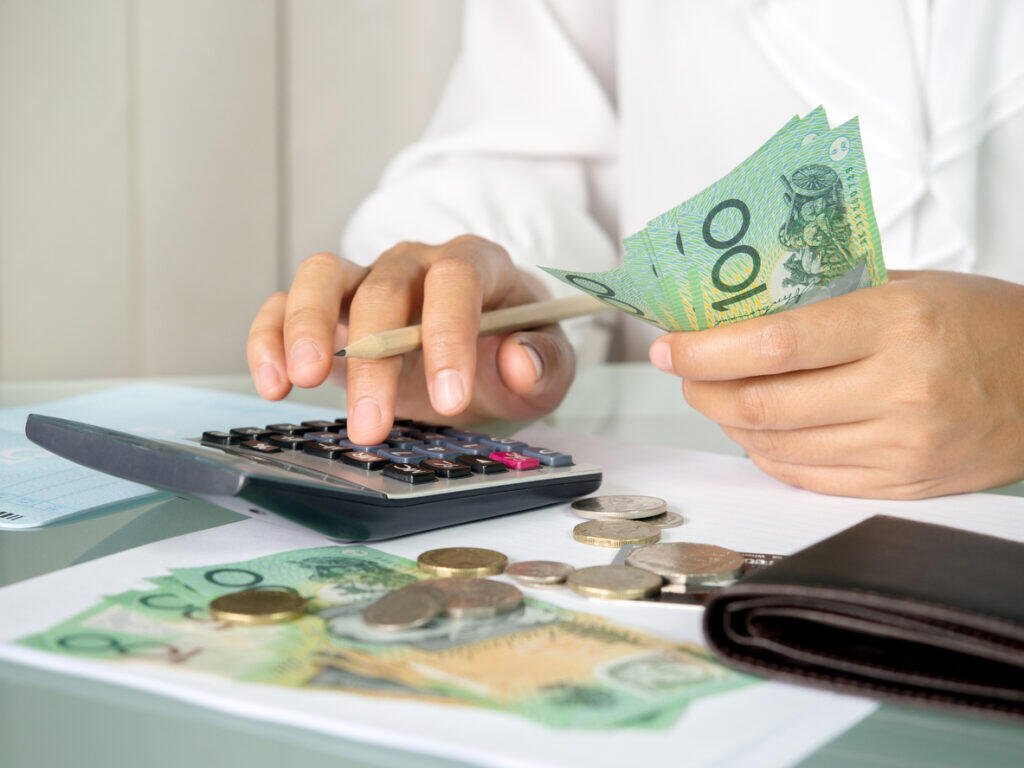 Person calculating finances, counting Australian dollars, managing cashflow and debt.
