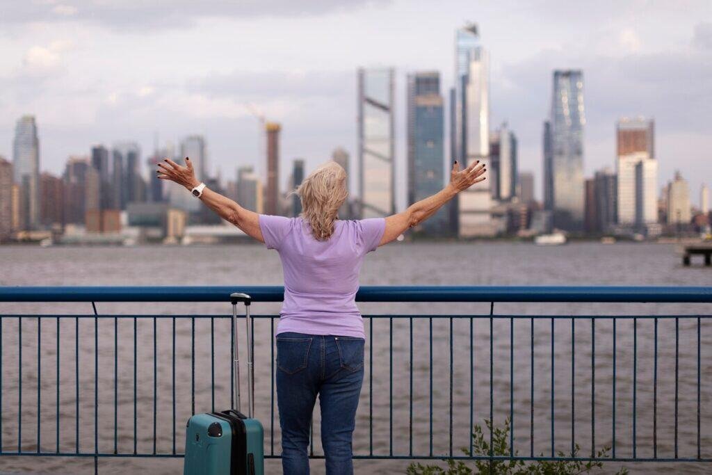 Woman with arms outstretched, overlooking city skyline, enjoying retirement.