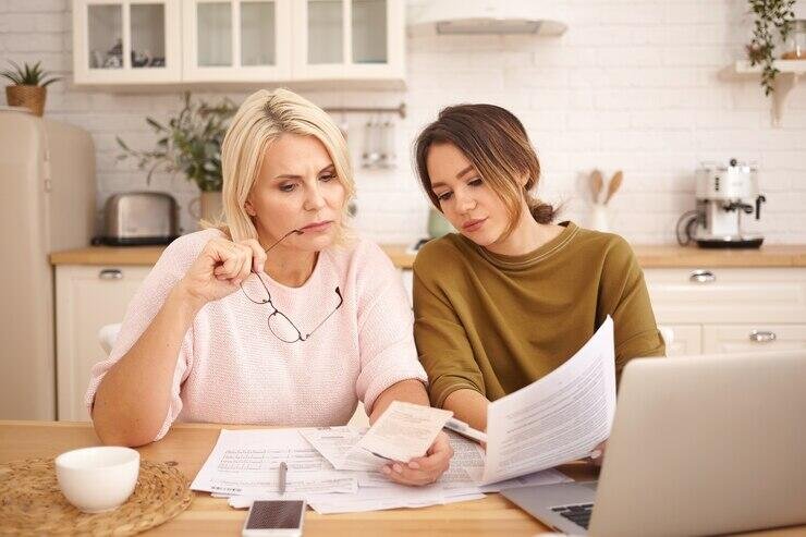 Two women review paperwork, possibly financial documents, for their Adelaide small business.